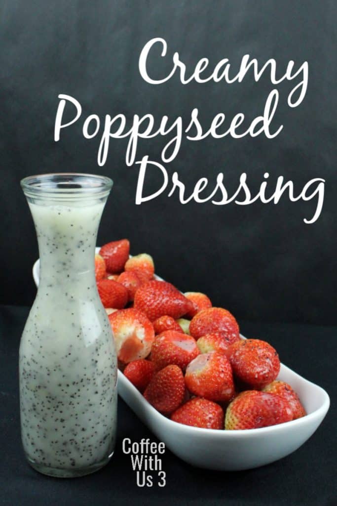 Creamy poppyseed dressing in small carafe with strawberries in a dish next to it.