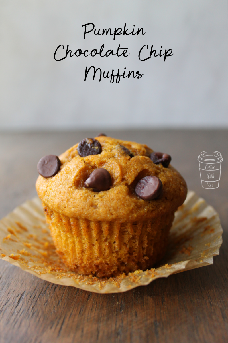 One delicious Pumpkin Chocolate Chip Muffin sitting on an open muffin liner atop a brown wooden countertop.