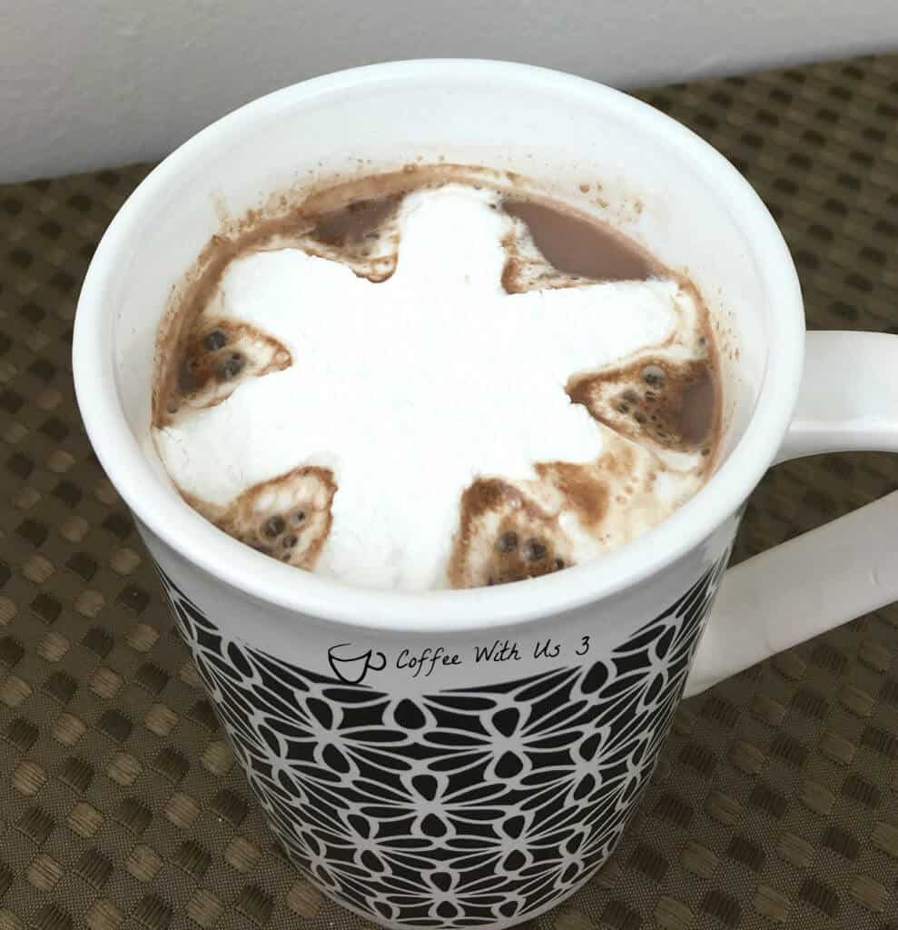 Peppermint flavored snowflake shaped marshmallow floating in a cup of cocoa.